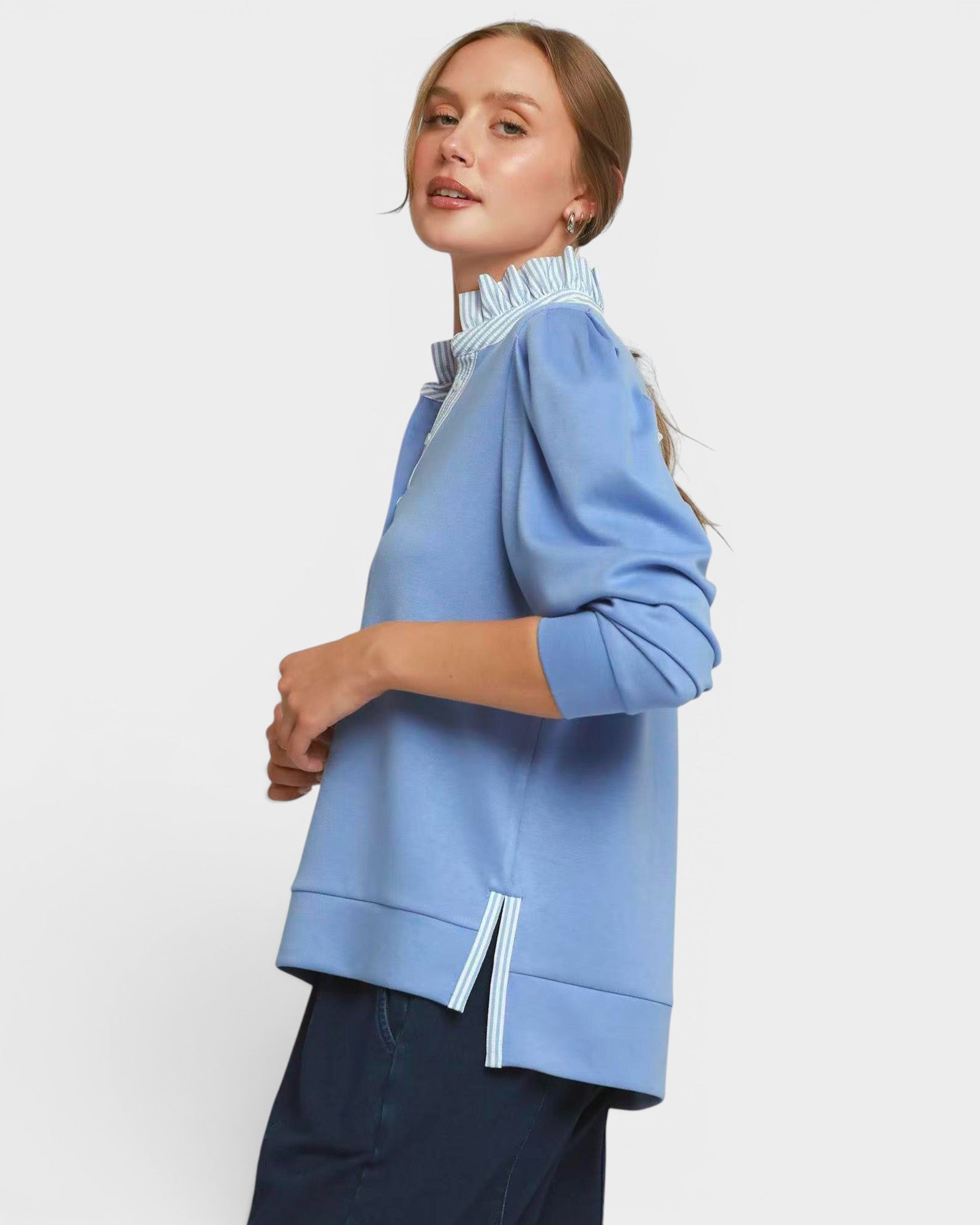 Woman wearing a light blue jacket with a white collar on a plain background