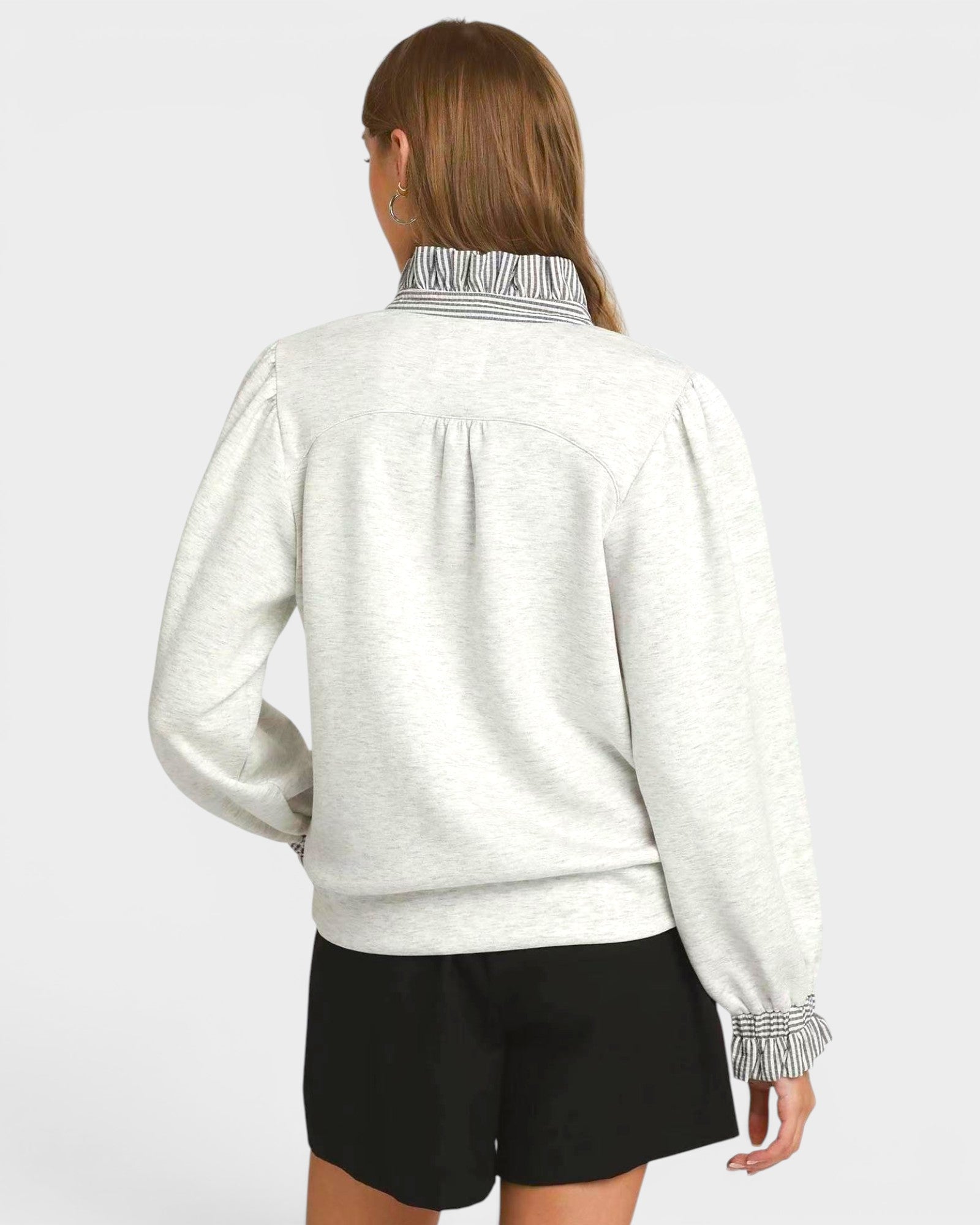 Person wearing a light gray jacket with black shorts on a white background