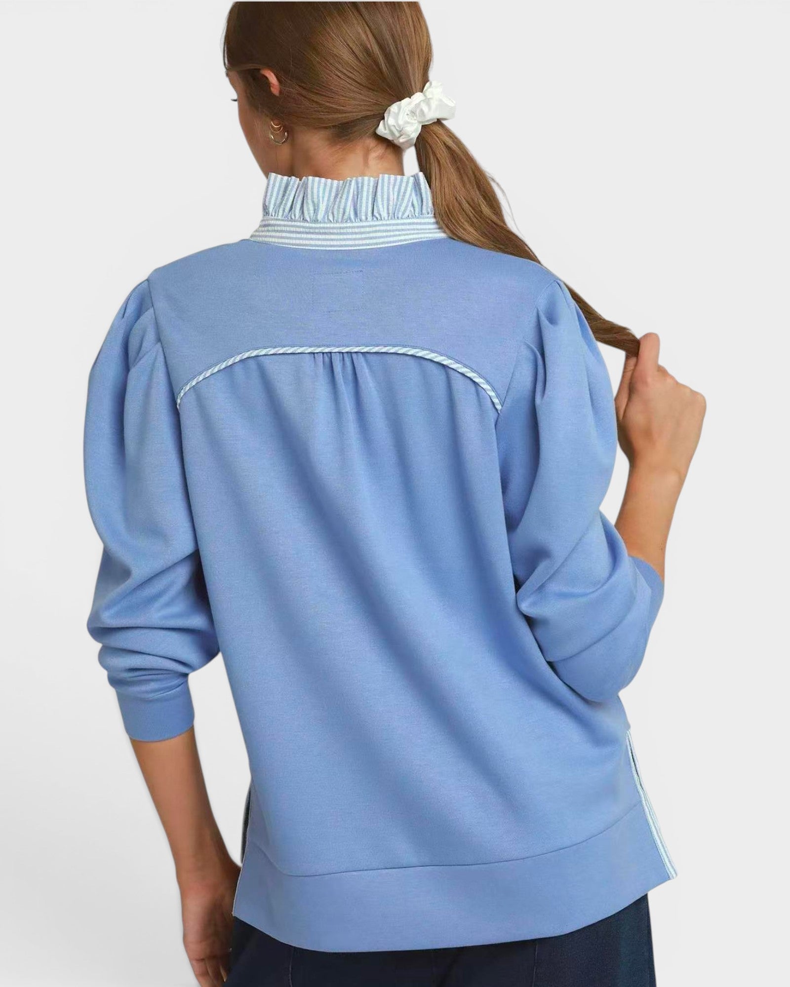 Person wearing a blue long-sleeve top with a white background