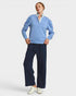 Person wearing a light blue sweater over a white shirt with navy pants on a white background
