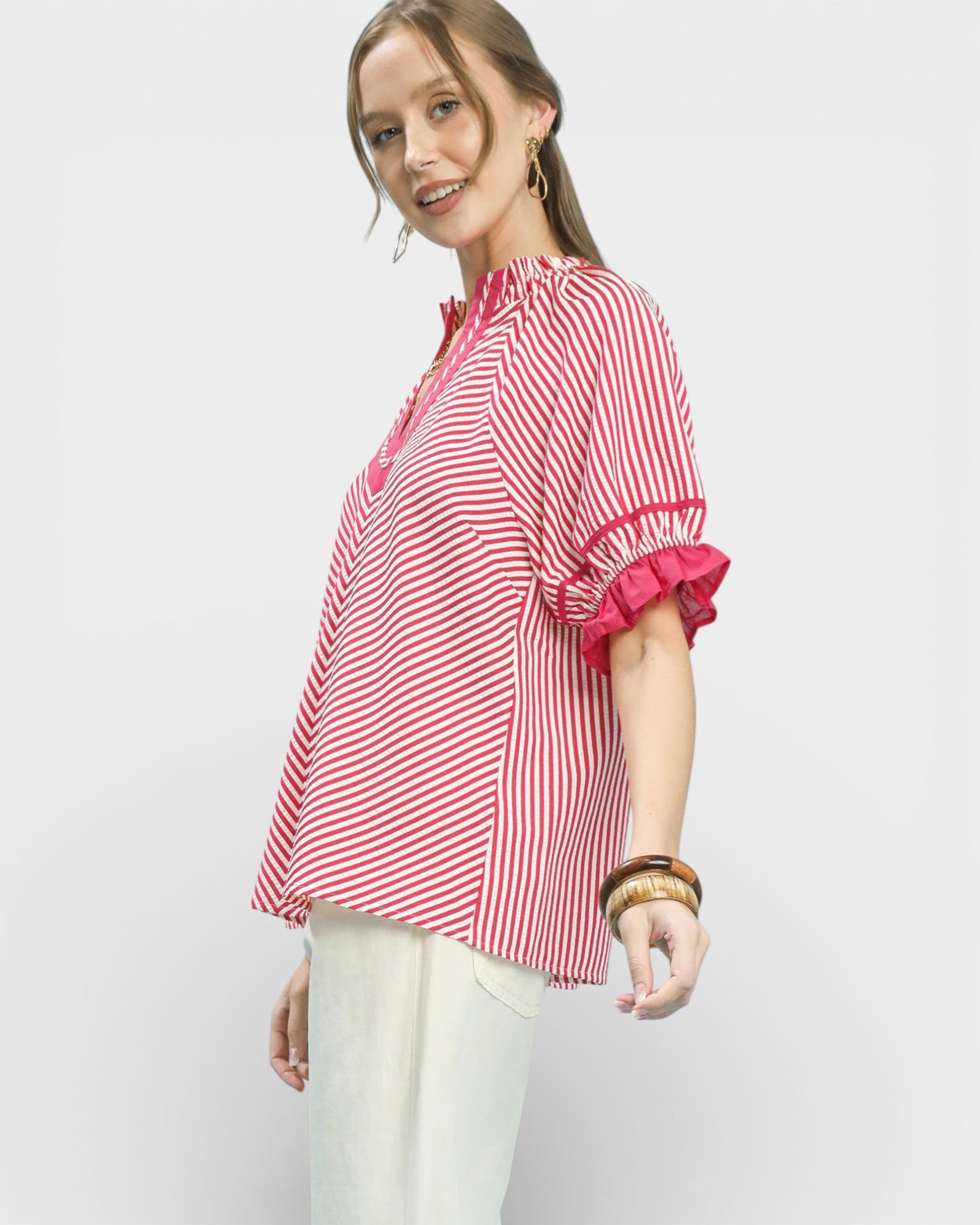 Woman wearing a red and white striped blouse with ruffled sleeves on a light gray background