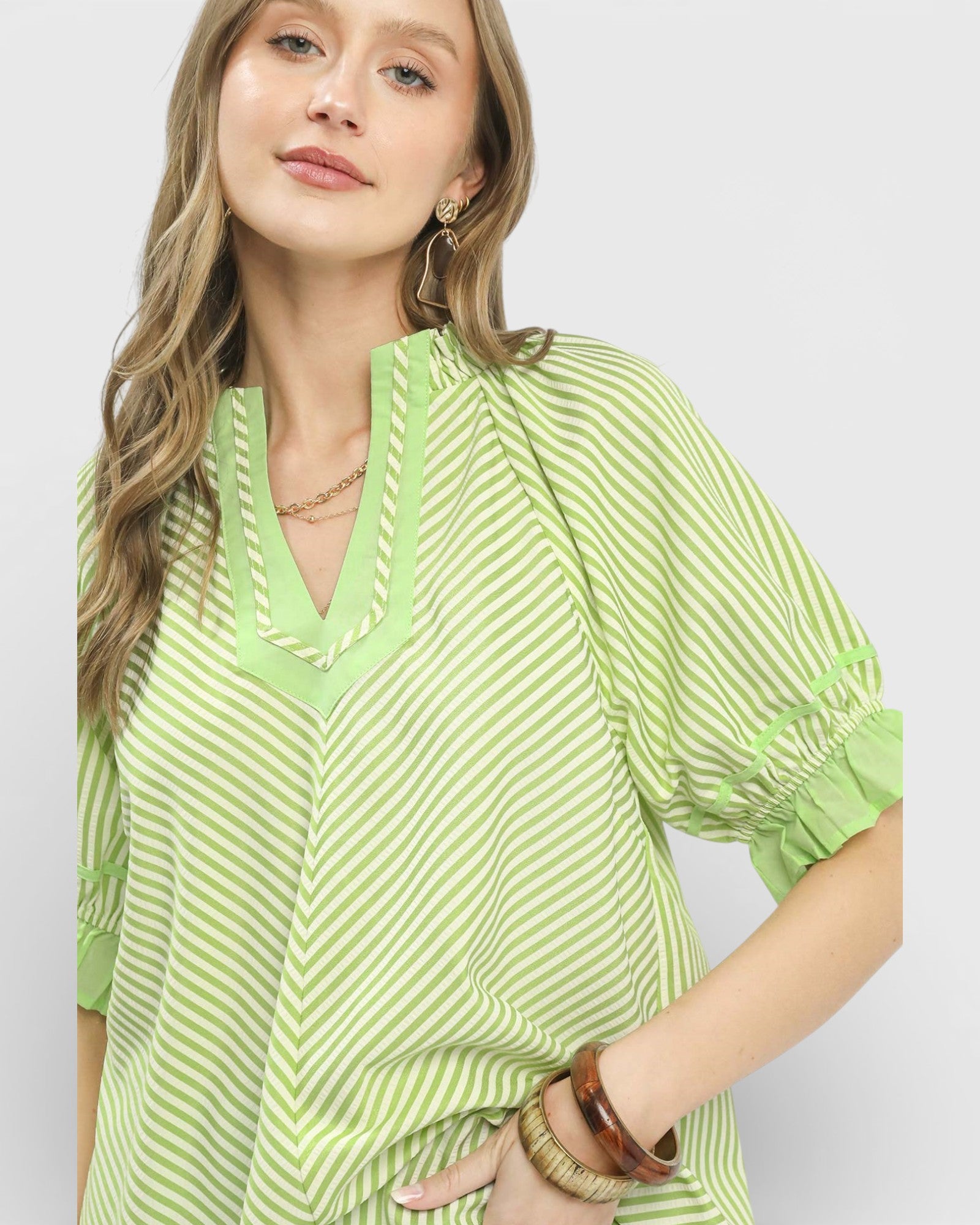 Woman wearing a green and white striped shirt on a plain background