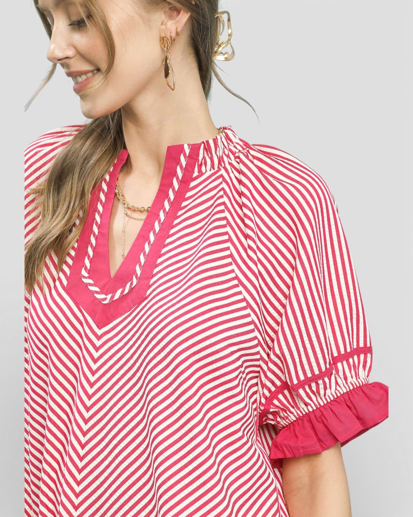 Woman wearing a red and white striped blouse on a gray background