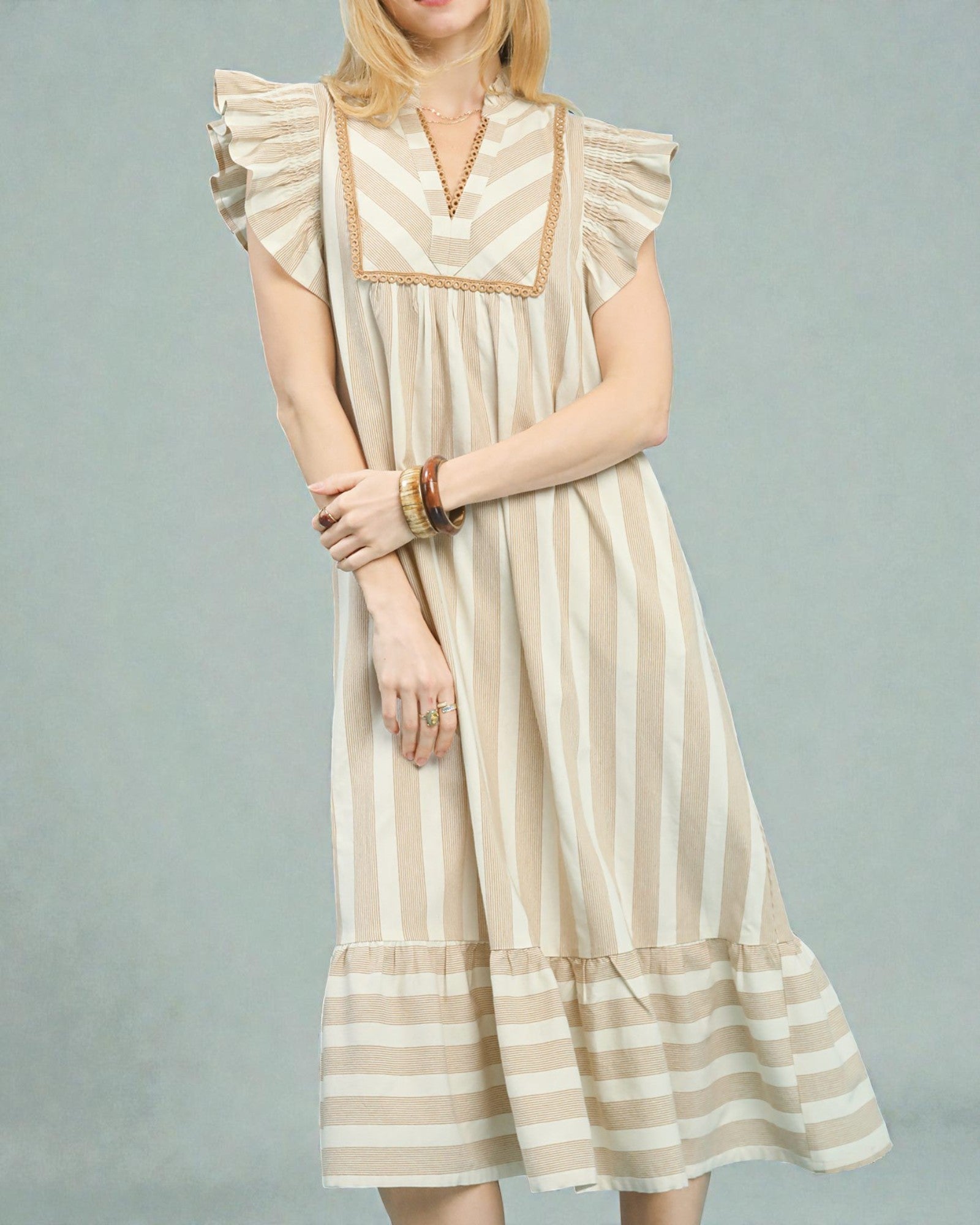 Woman wearing a beige and white striped dress on a gray background
