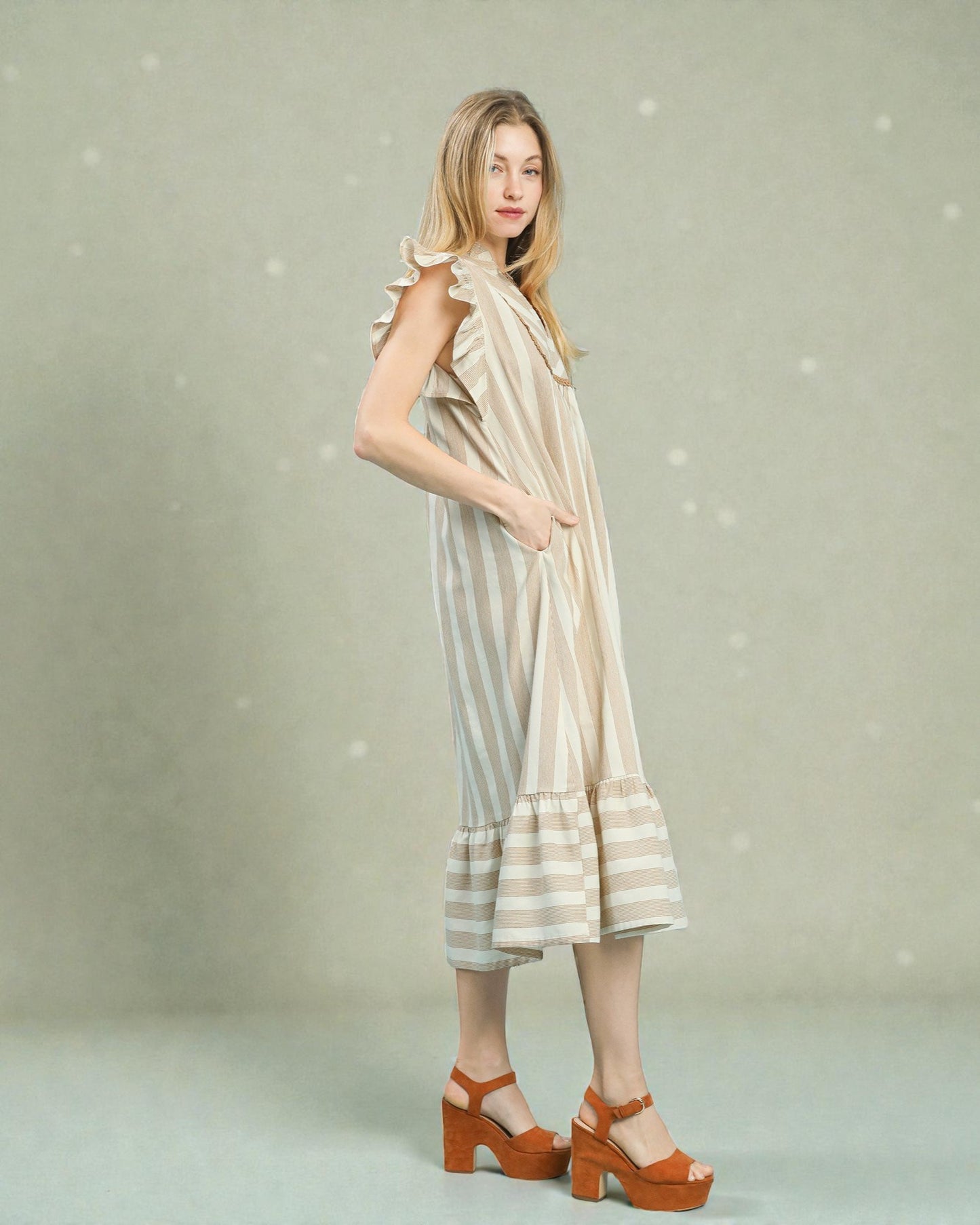 Woman wearing a striped dress with ruffled sleeves against a light background