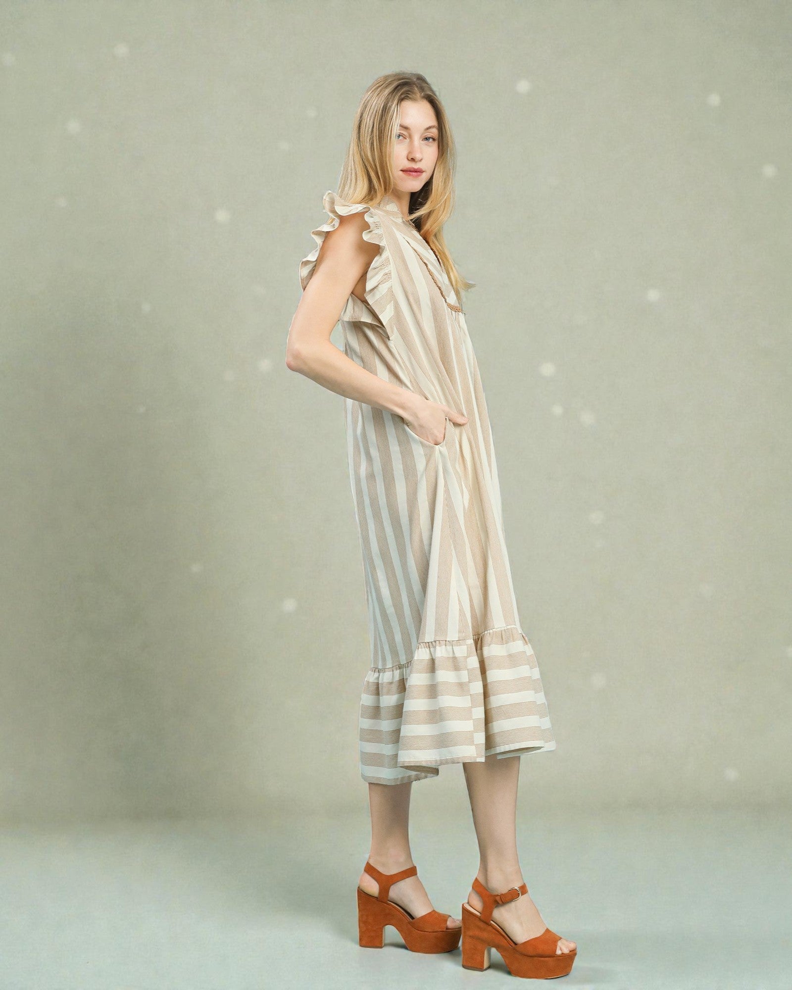 Woman wearing a striped dress with ruffled sleeves against a light background