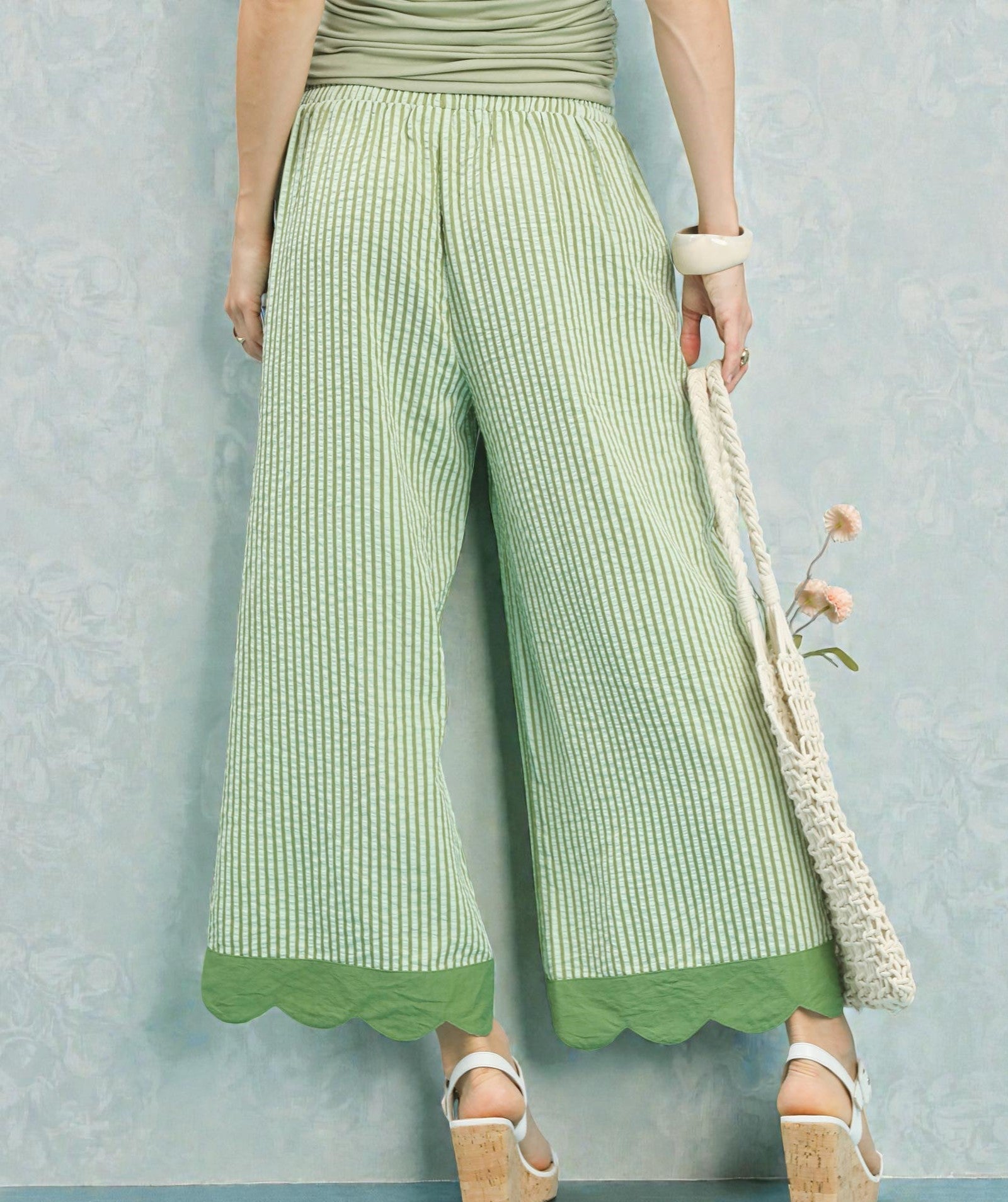 Person wearing green striped pants with a plain background