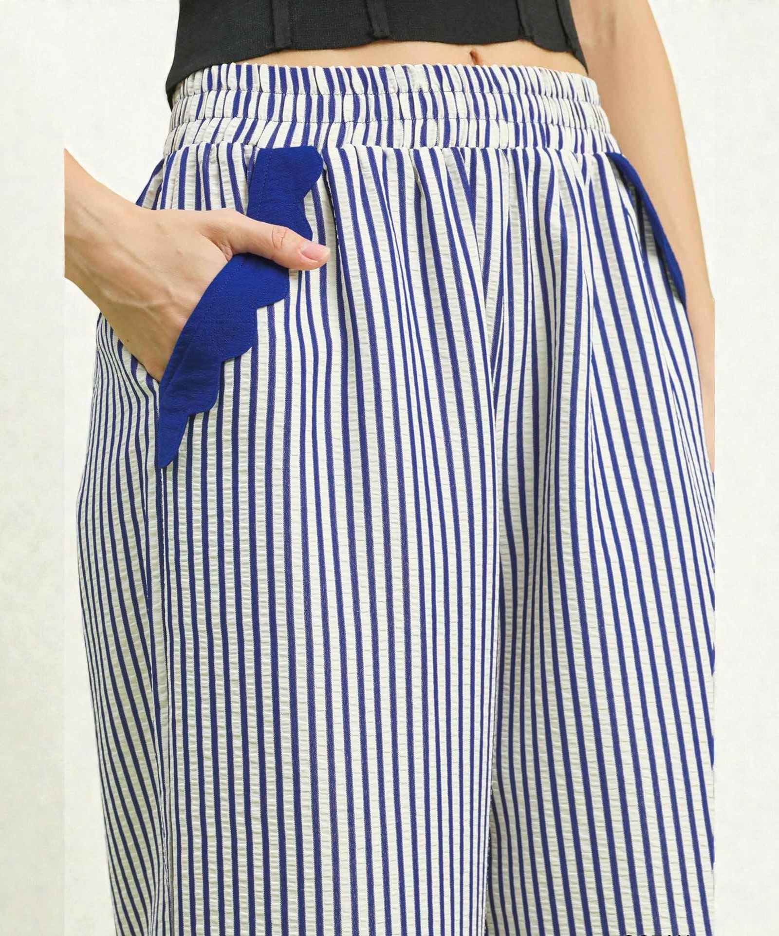 Blue and white striped pants with a blue towel in a pocket on a plain background