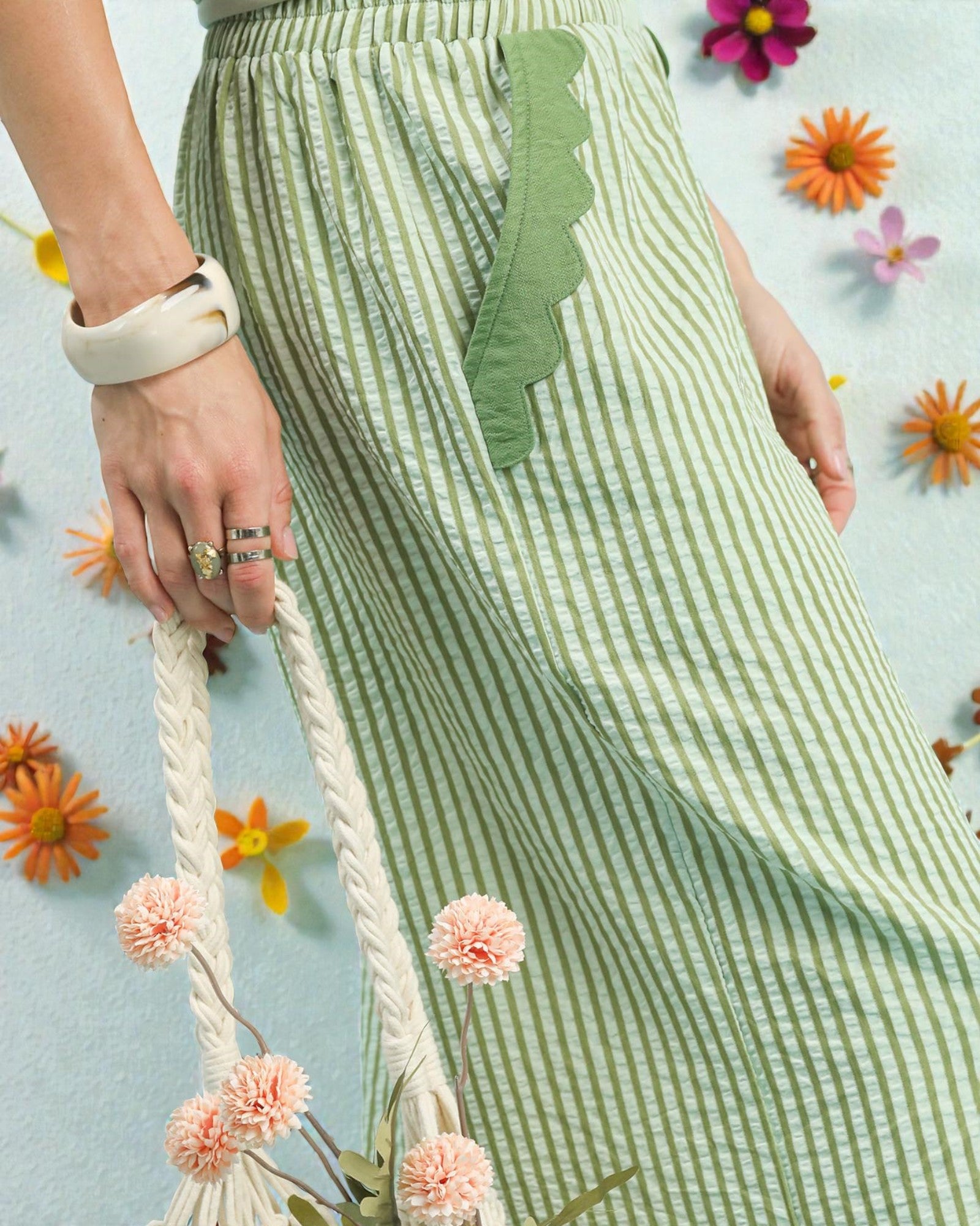 Green and white striped skirt with a decorative leaf detail, held by a person against a floral background.