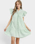 Woman wearing a light green dress with ruffled sleeves on a white background