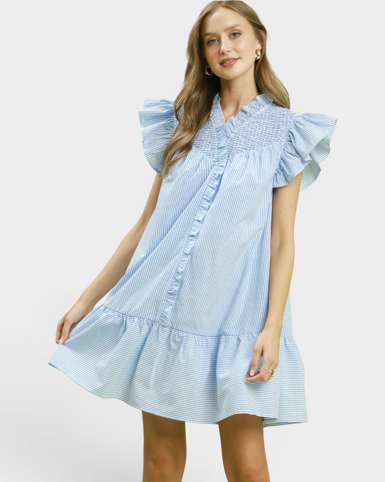 Woman wearing a light blue dress with ruffled sleeves on a white background