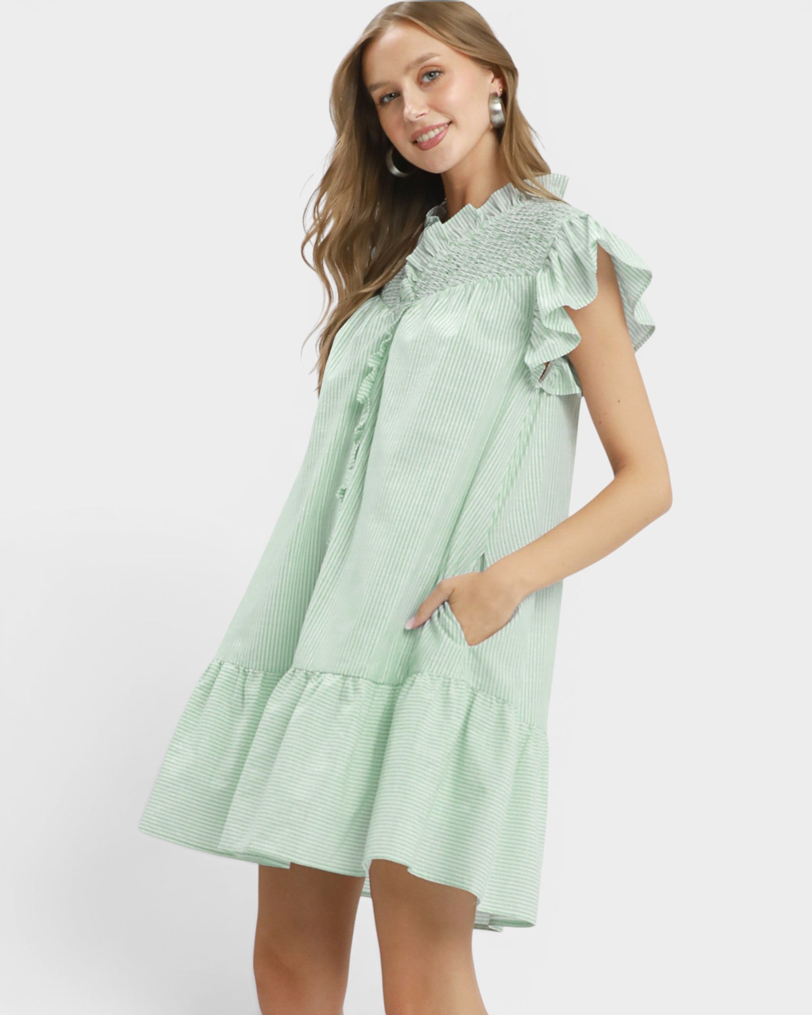 Woman wearing a light green dress with ruffled sleeves on a white background