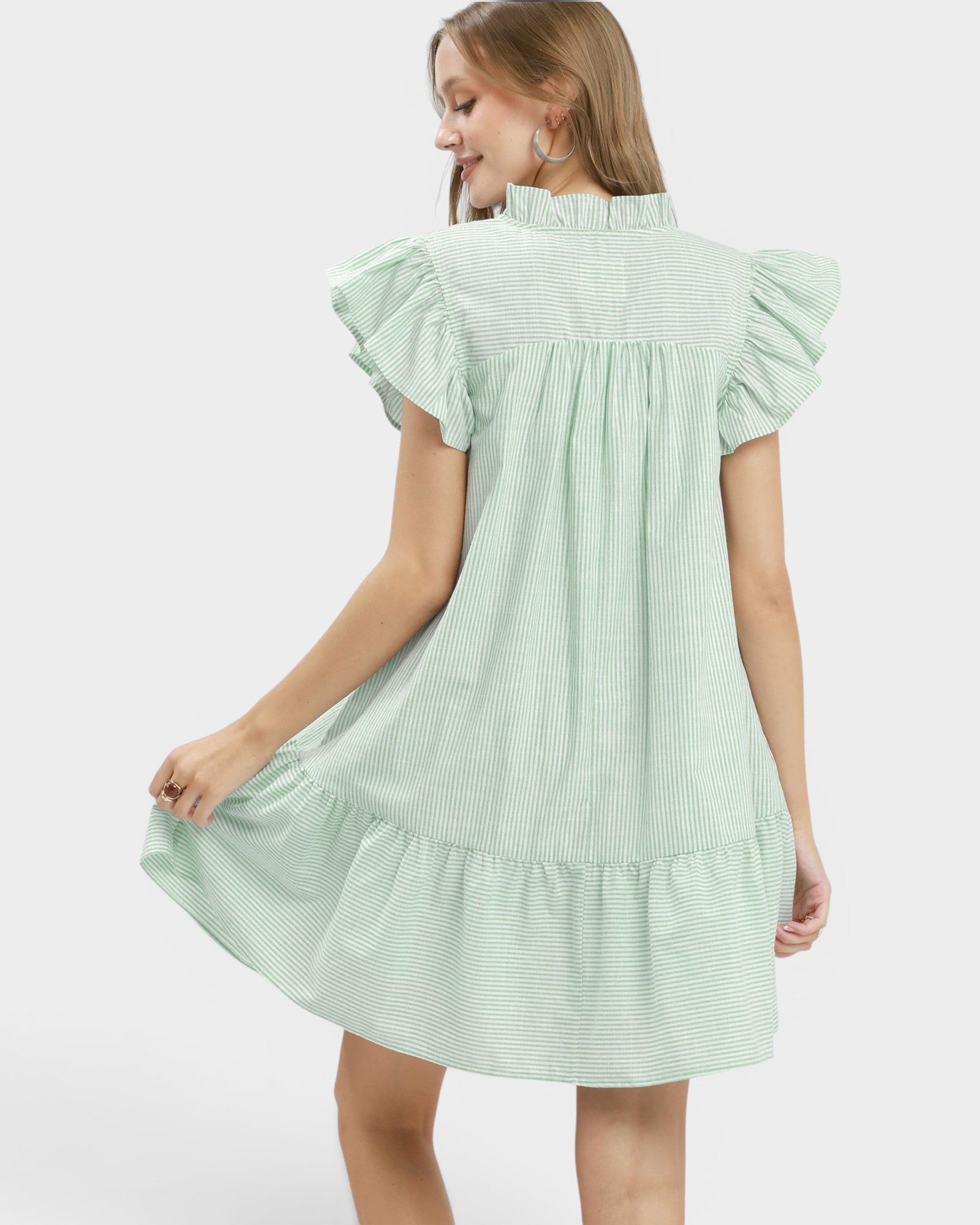 Woman wearing a light green dress with ruffled sleeves on a white background