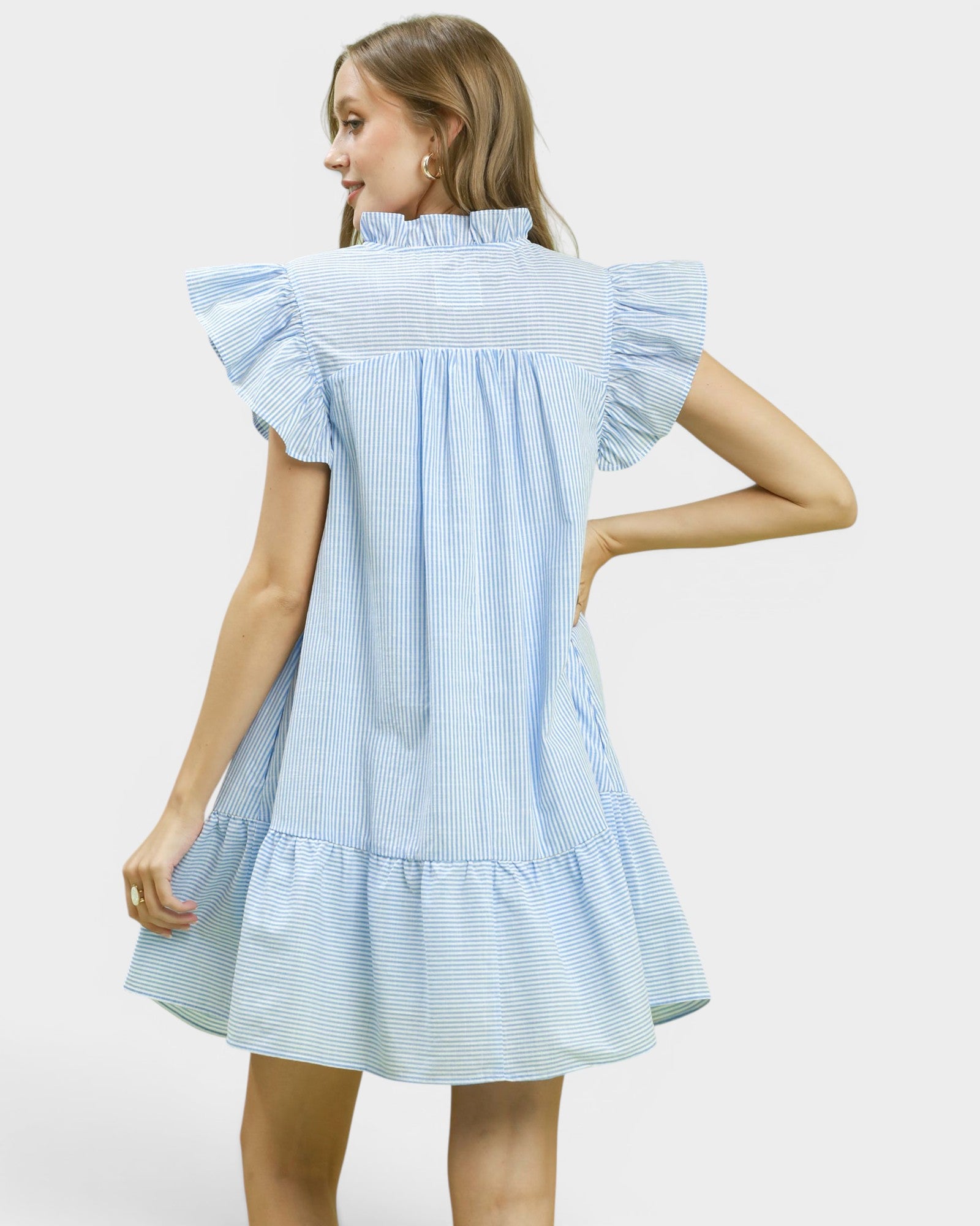 Woman wearing a light blue dress with ruffled sleeves on a white background