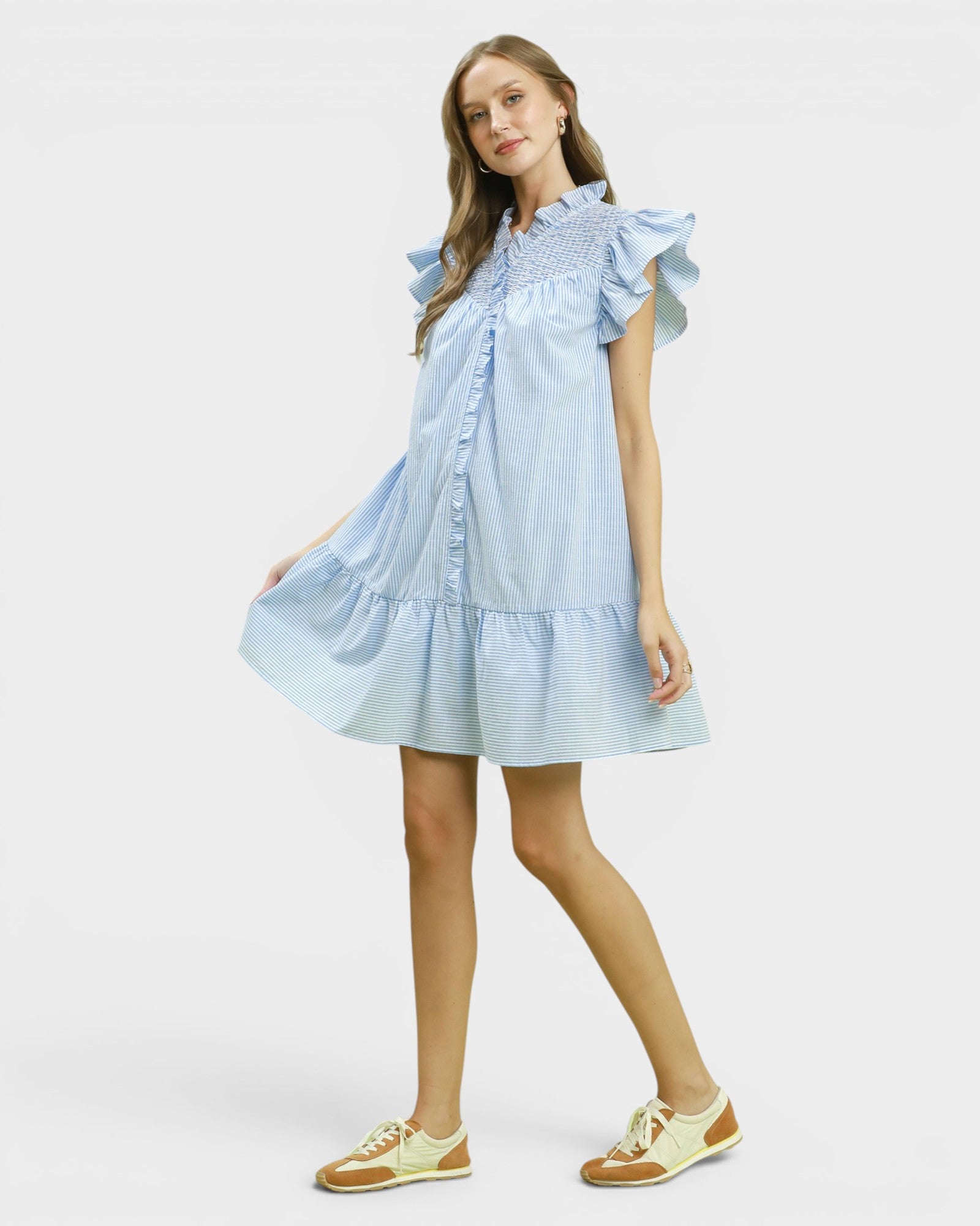 Woman wearing a light blue dress with ruffled sleeves on a white background