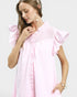 Woman wearing a pink dress with ruffled sleeves on a light gray background