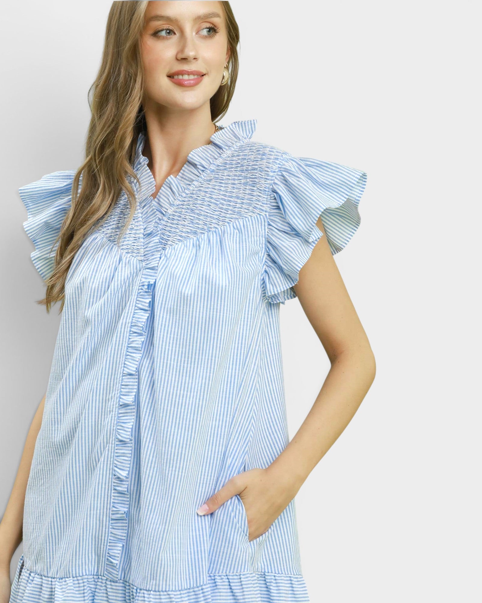 Woman wearing a blue and white striped dress with ruffled sleeves against a plain background