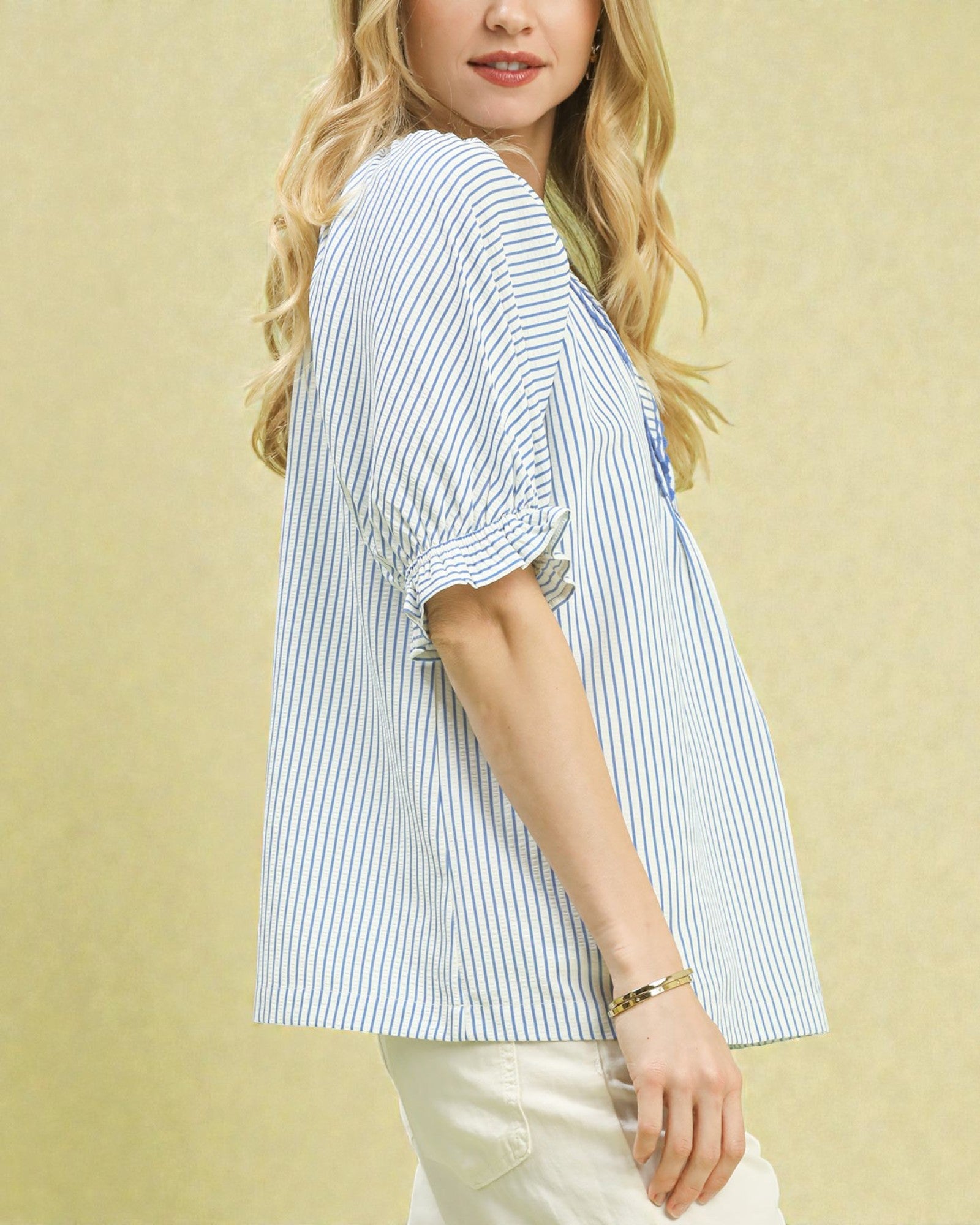 Woman wearing a blue and white striped shirt against a beige background
