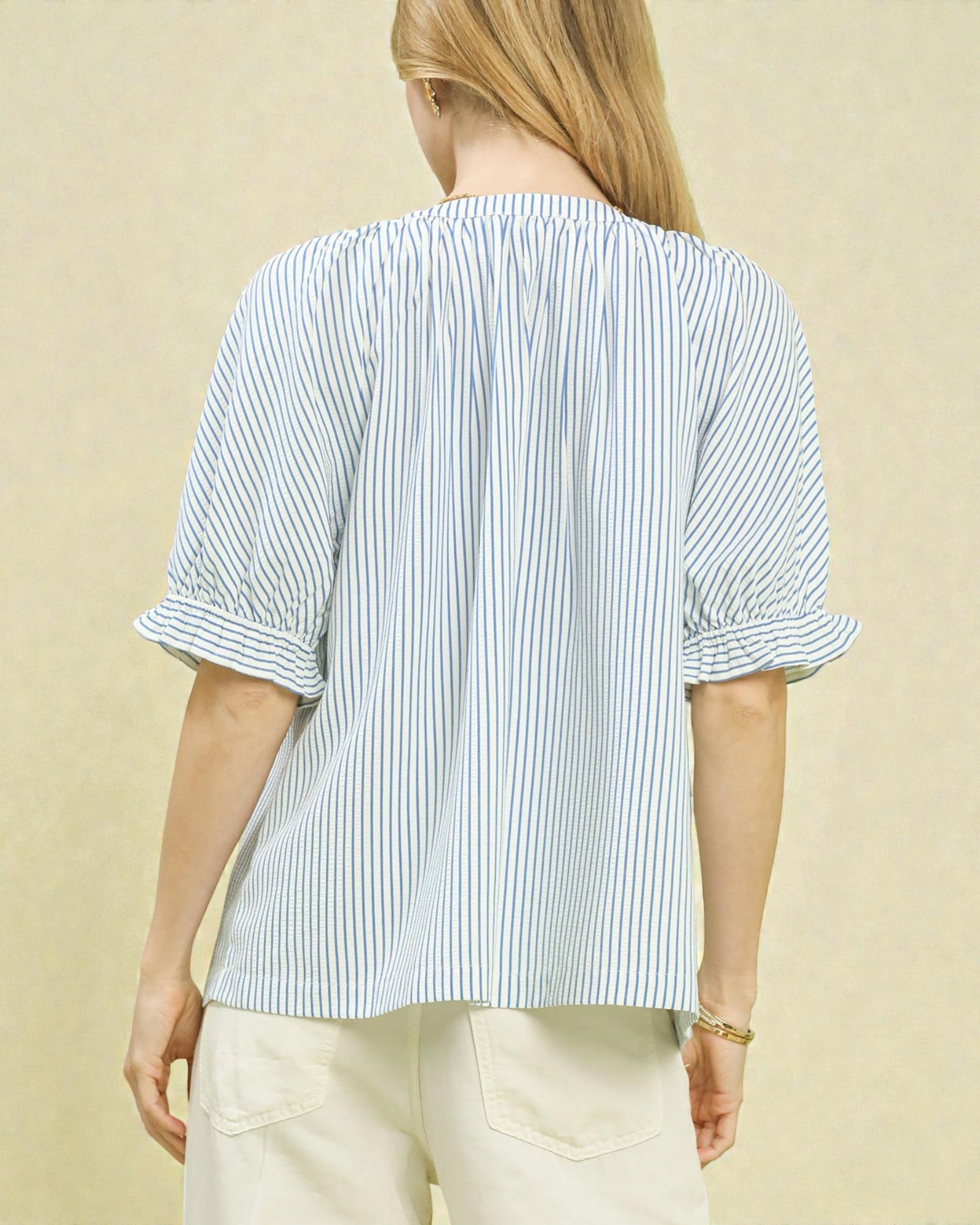 Person wearing a blue and white striped shirt against a beige background