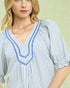Woman wearing a blue and white striped shirt with decorative trim on a light green background
