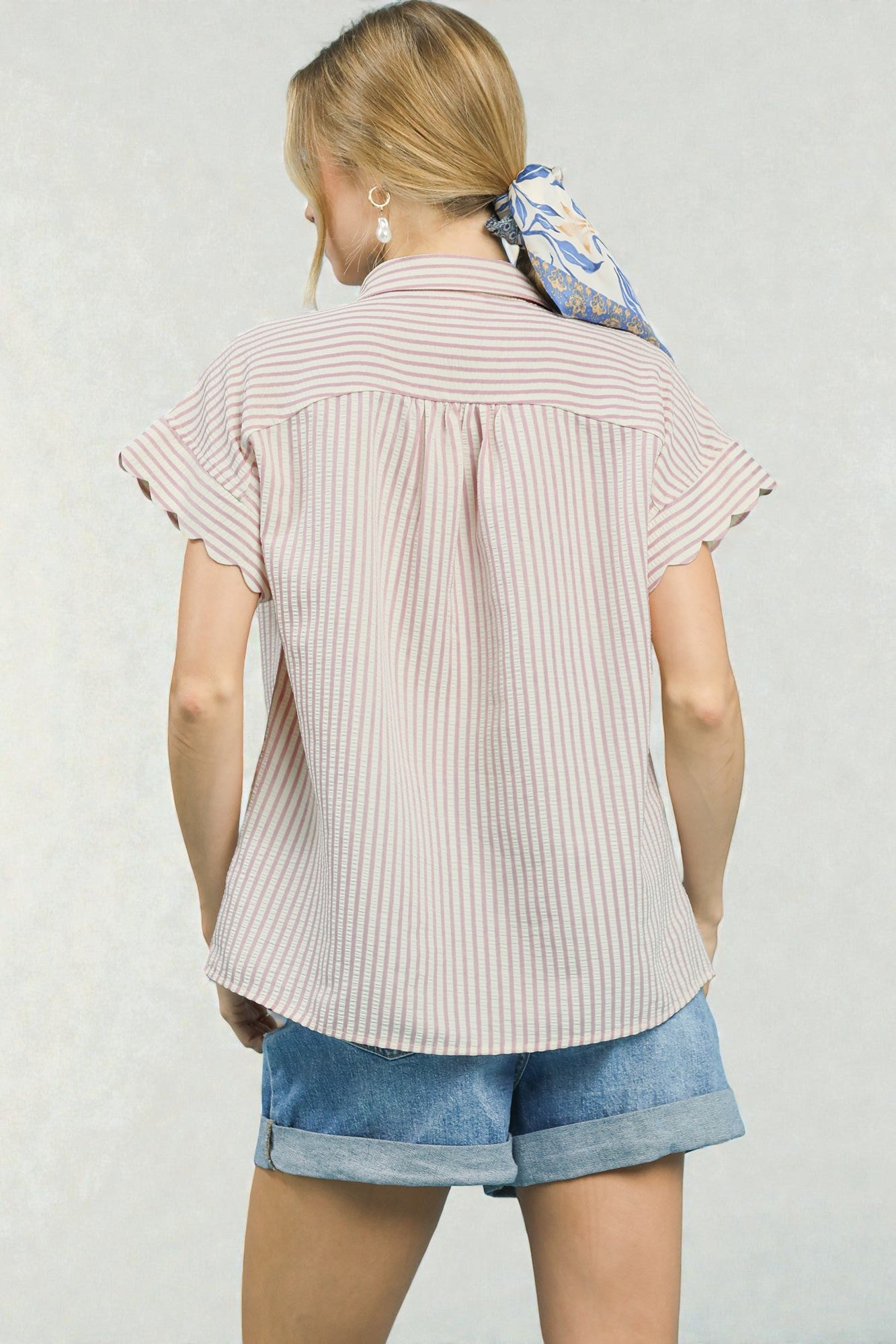 Person wearing a striped shirt and denim shorts with a white background