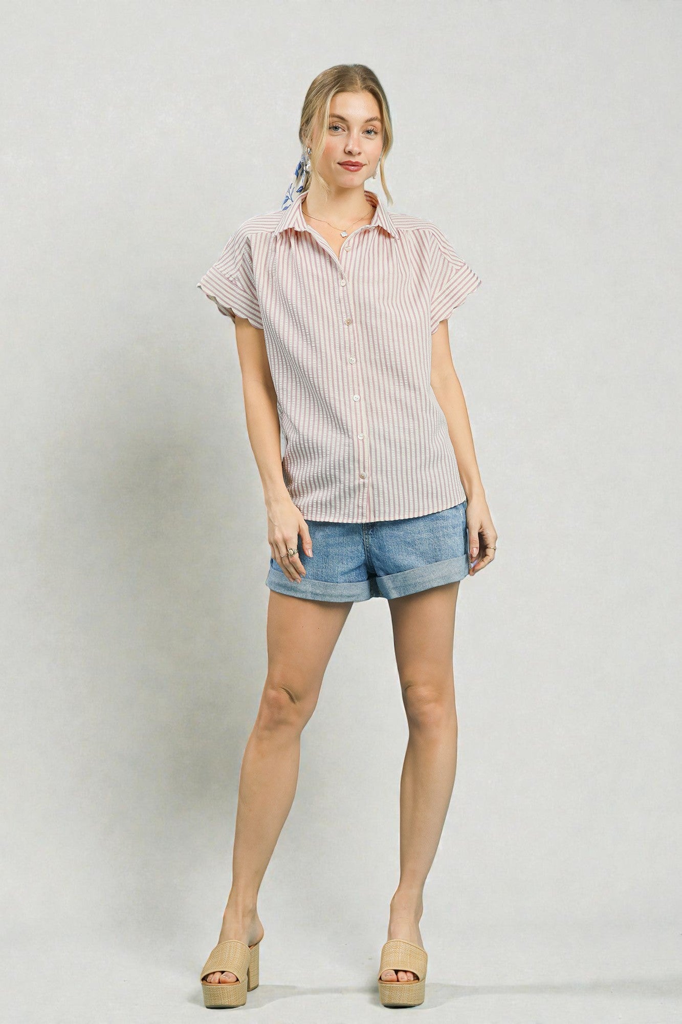 Woman wearing a striped shirt and denim shorts on a plain background