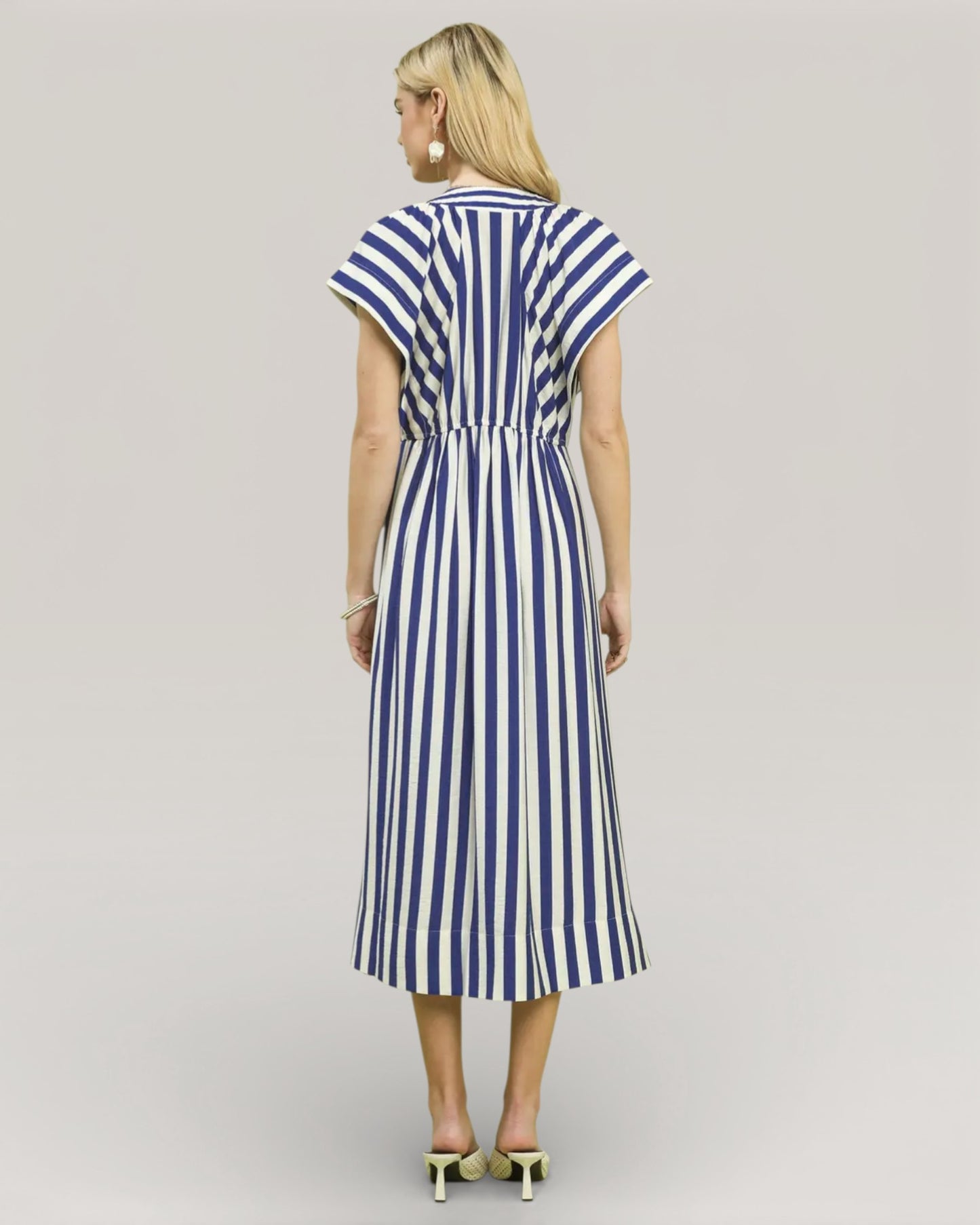 Woman wearing a blue and white striped dress on a plain background