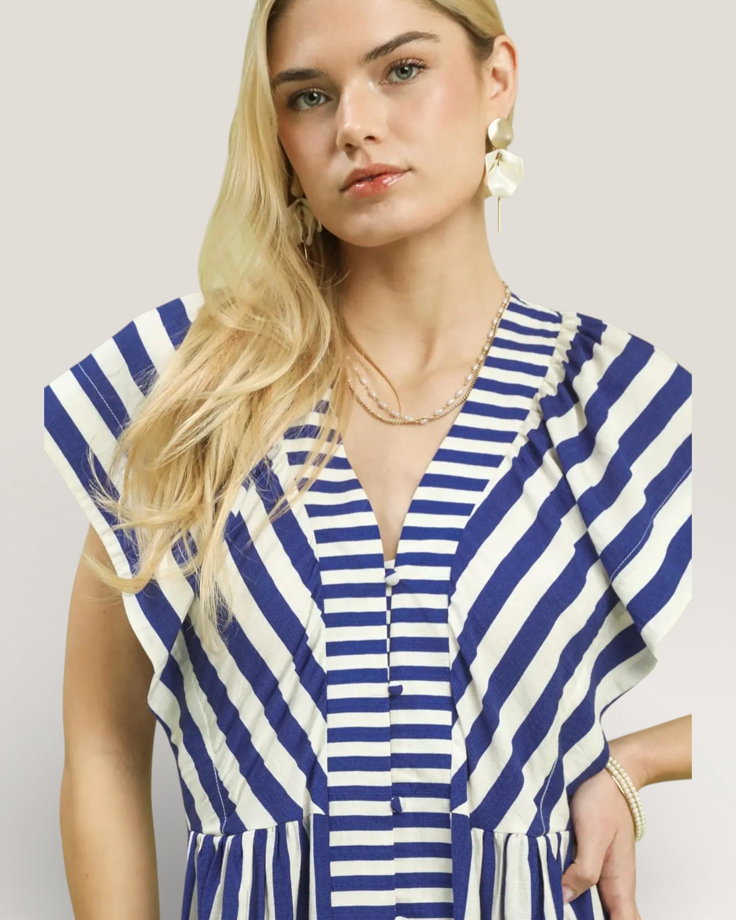 Woman wearing a blue and white striped dress against a plain background