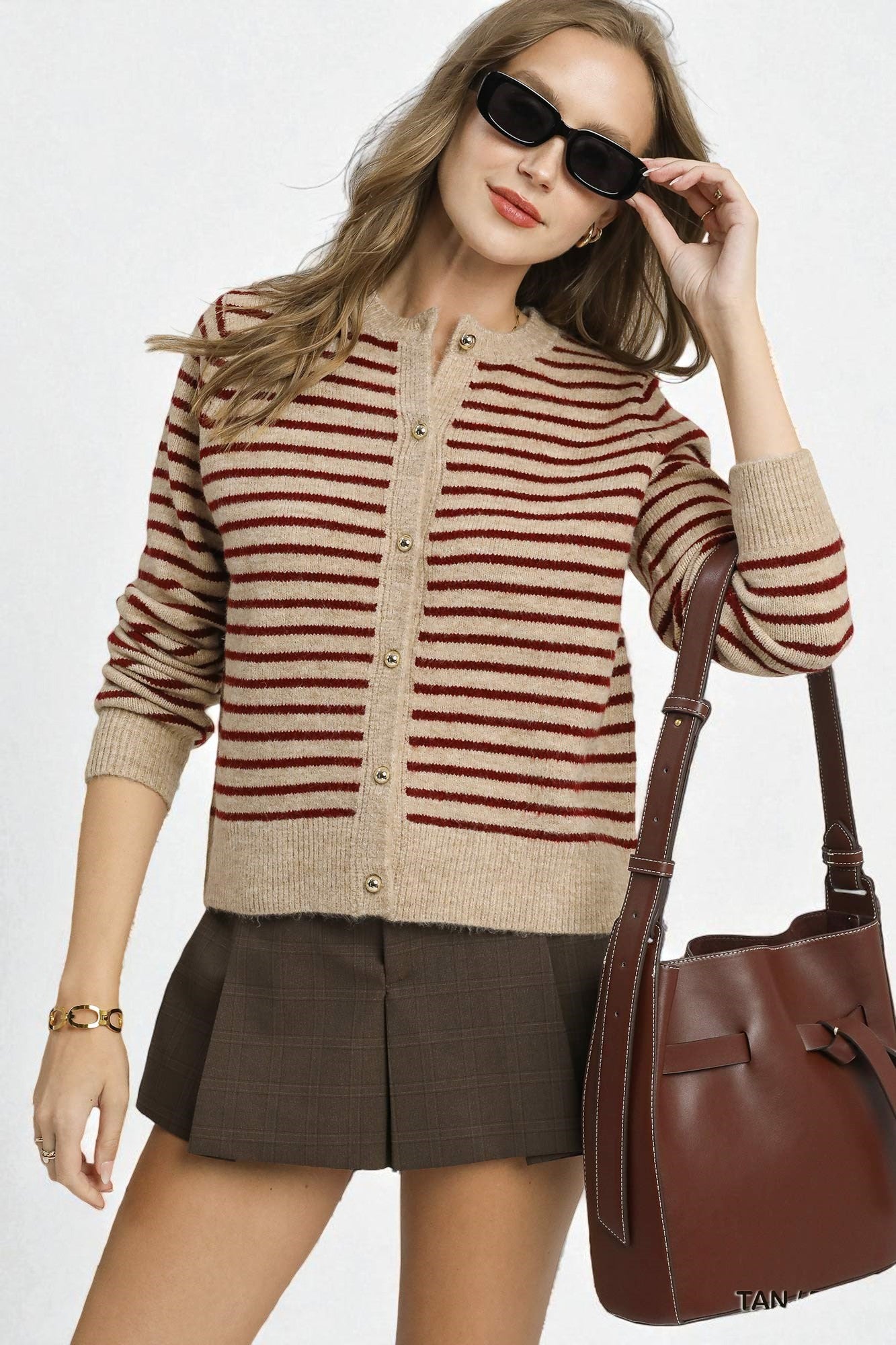 Woman wearing a striped sweater and skirt with a brown handbag on a white background