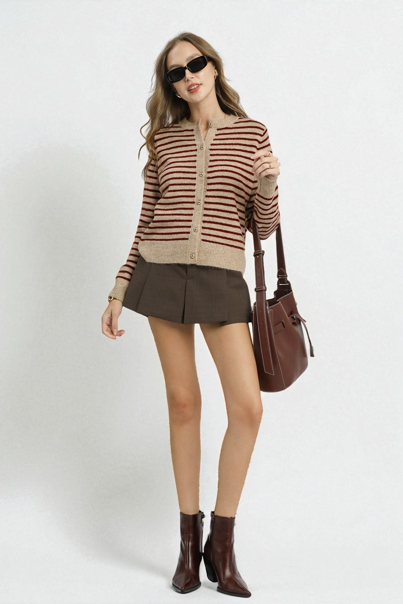 Woman wearing a striped sweater, skirt, and boots with a handbag on a white background