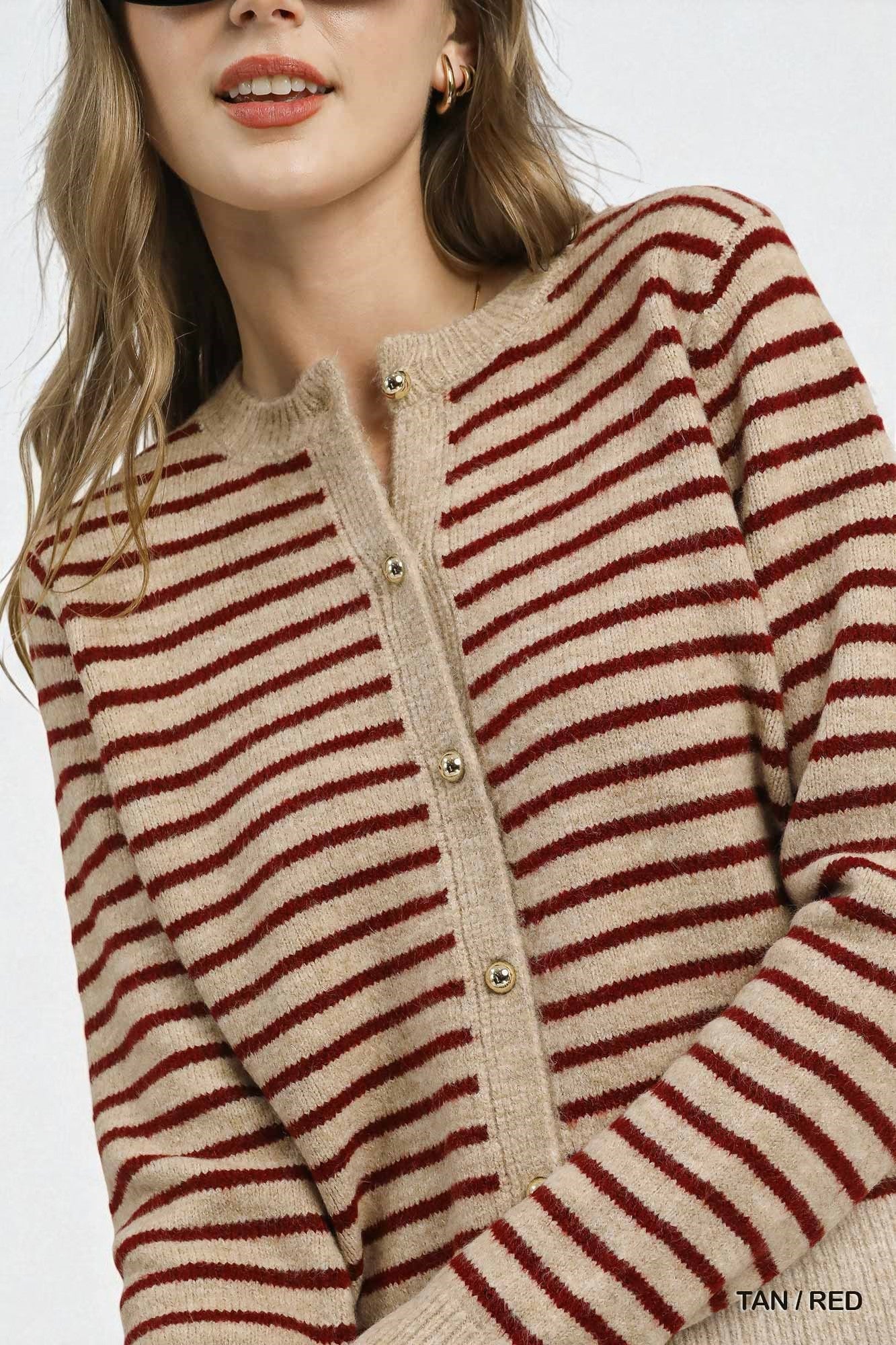 Close-up of a person wearing a beige and red striped sweater on a white background