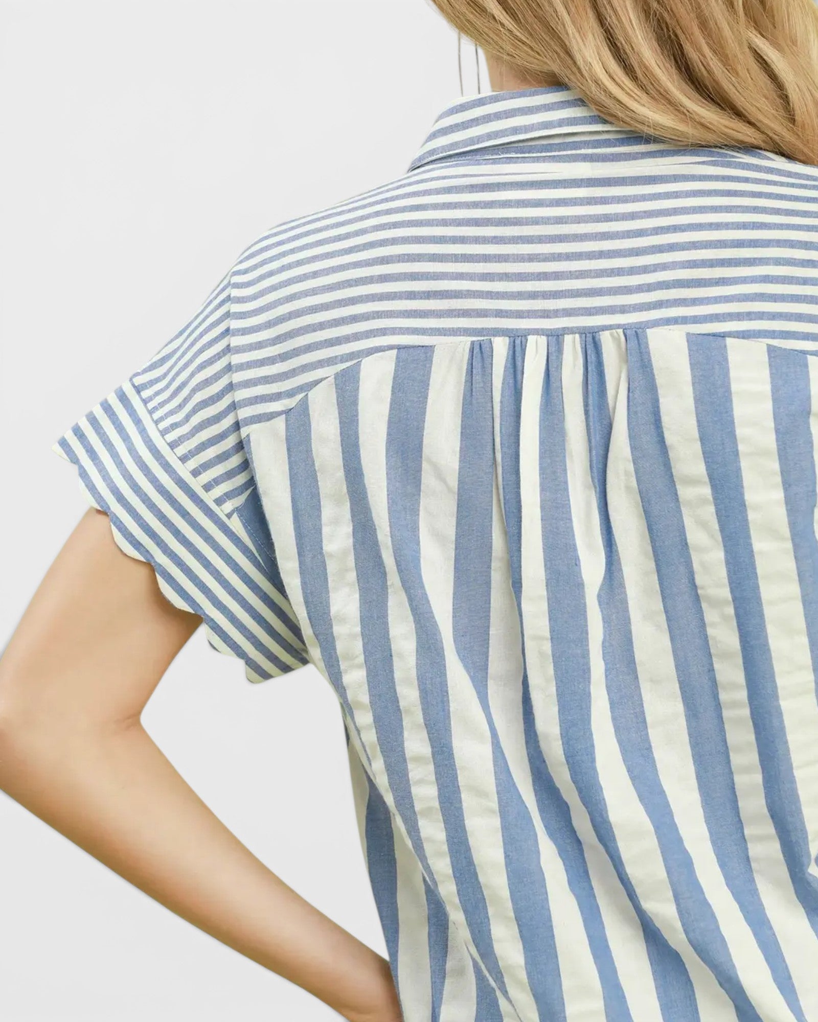 Close-up of a person wearing a blue and white striped shirt against a light background