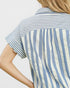 Close-up of a person wearing a blue and white striped shirt against a light background