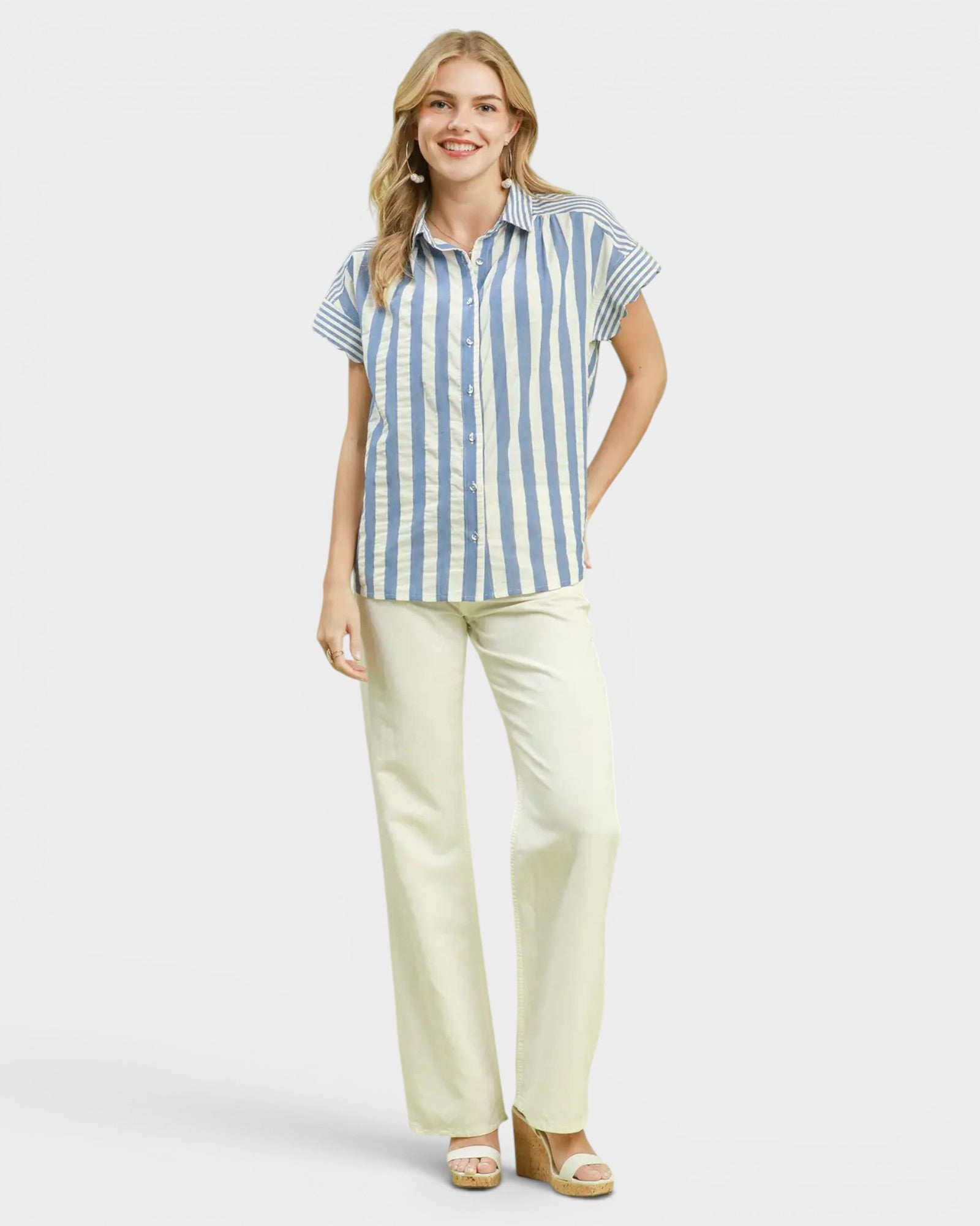 Woman wearing a blue and white striped shirt and light green pants on a white background