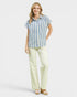Woman wearing a blue and white striped shirt and light green pants on a white background