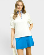 Woman wearing a white blouse with a blue skirt on a plain background
