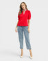 Woman wearing a red blouse and blue jeans with floral embroidery on a white background