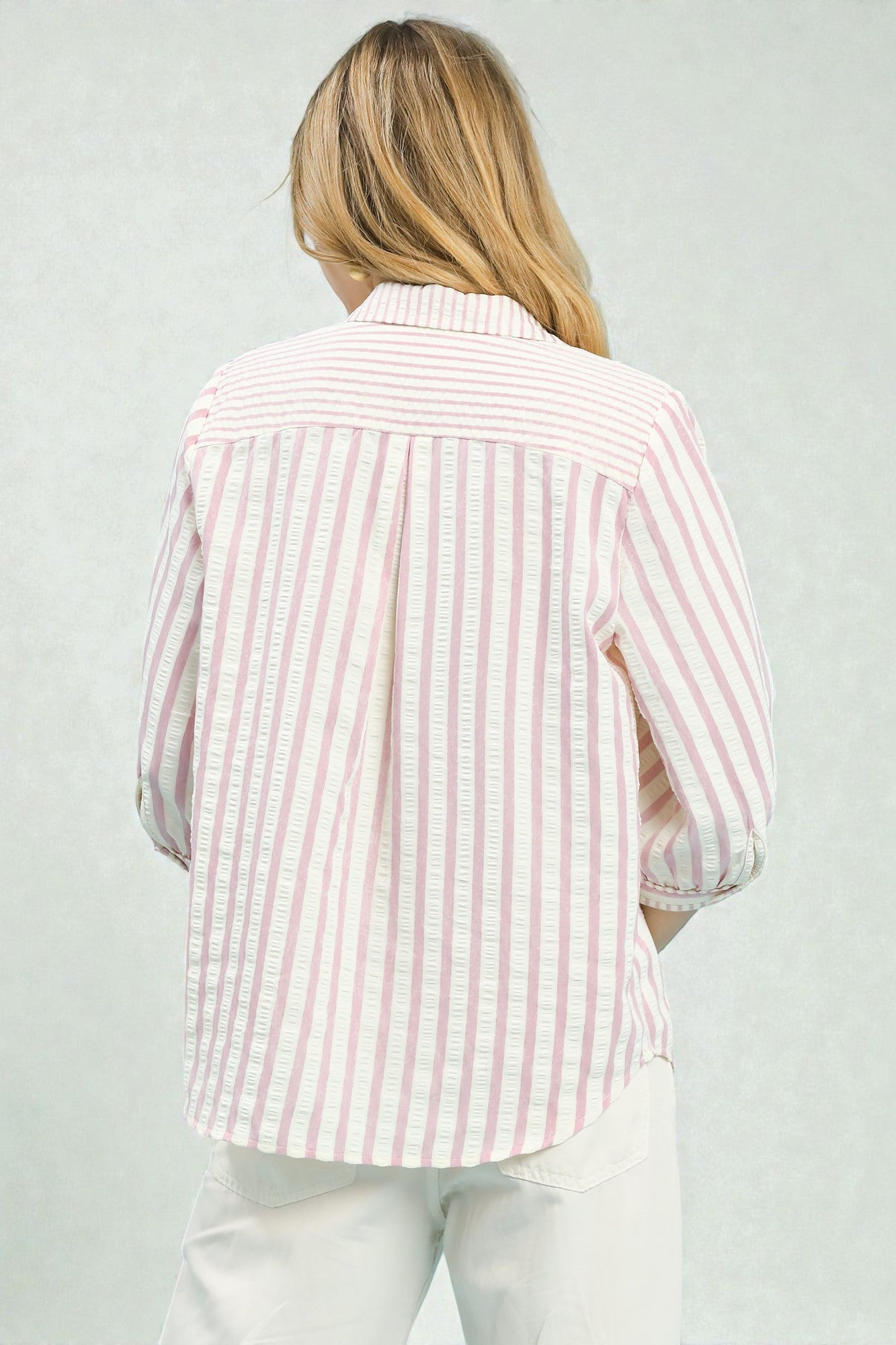 Person wearing a pink and white striped shirt against a light gray background