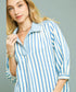 Woman wearing a blue and white striped shirt against a gray background