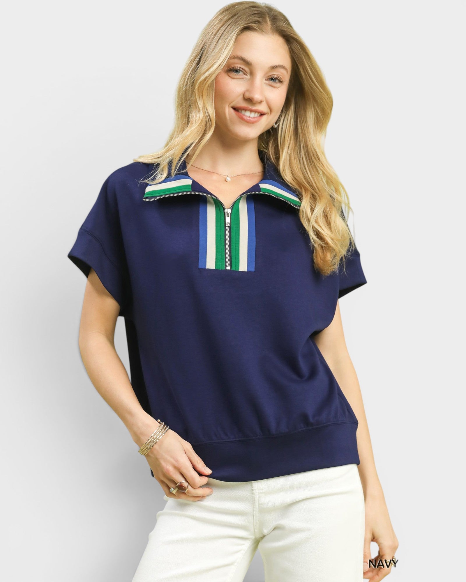 Woman wearing a navy blue top with a colorful zipper detail on a light gray background