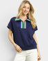 Woman wearing a navy blue top with a colorful zipper detail on a light gray background