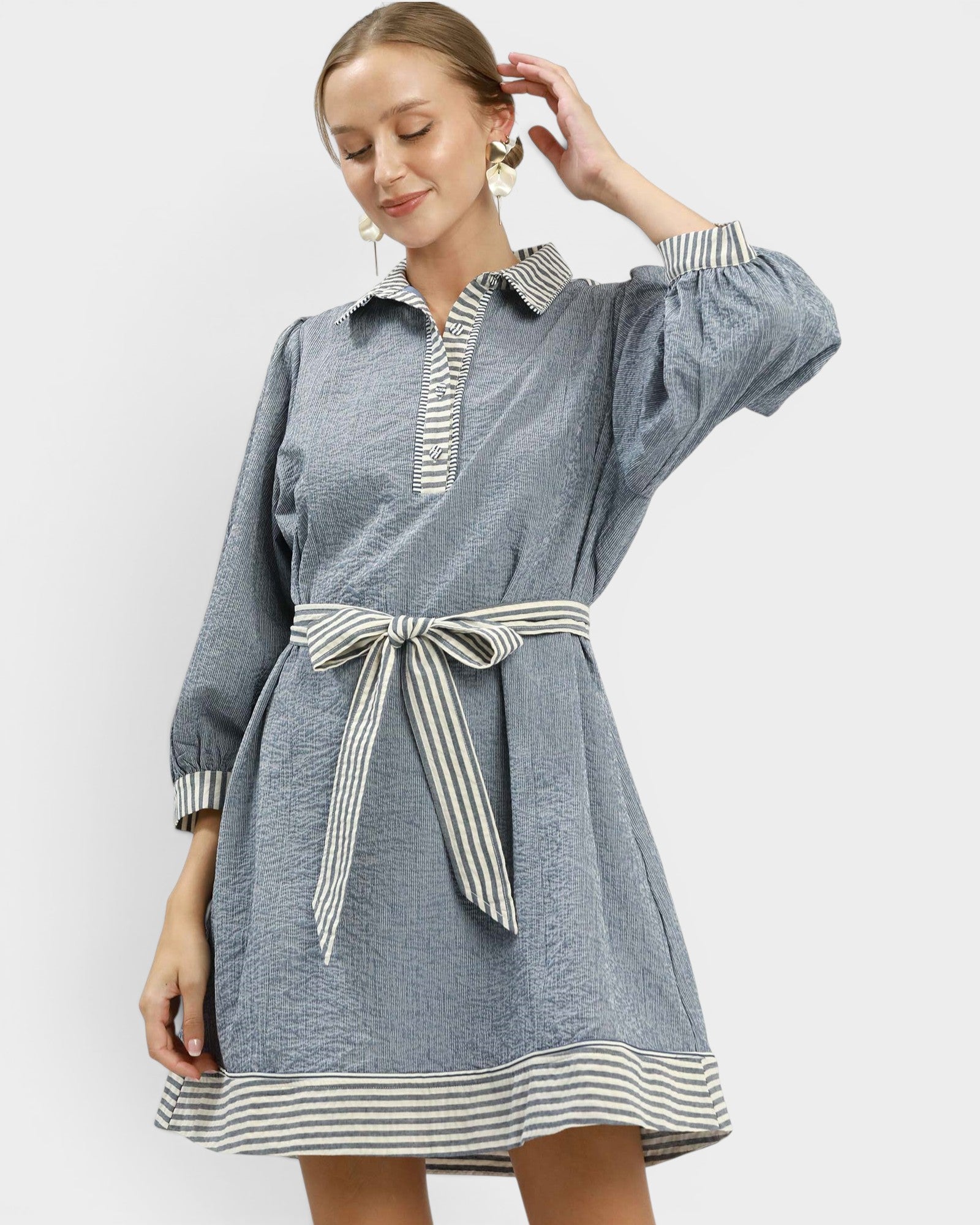 Woman wearing a blue dress with striped details on a white background