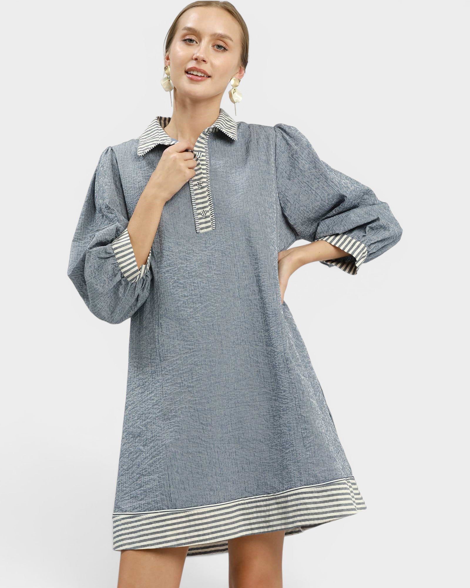 Woman wearing a blue dress with striped details on a white background