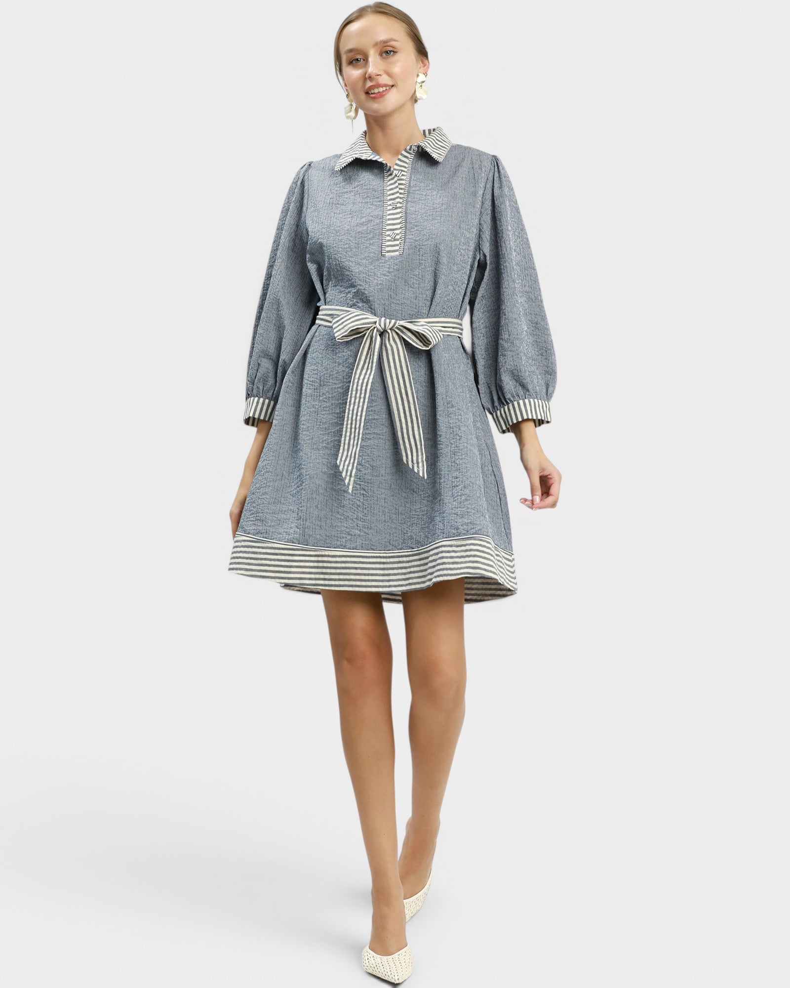 Woman wearing a blue dress with a belt on a white background