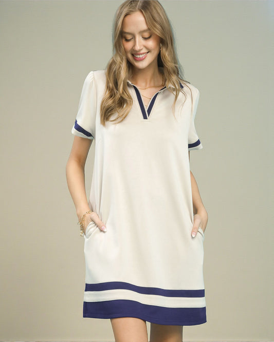 Woman wearing a white dress with blue accents on a plain background