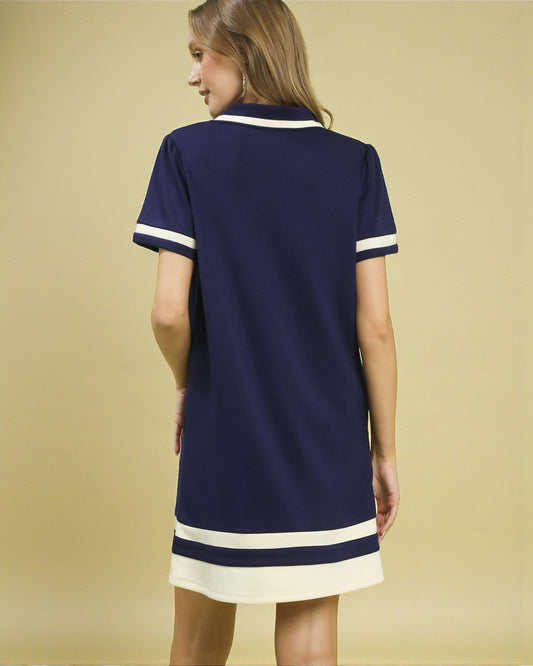 Woman wearing a navy dress with white trim on a beige background