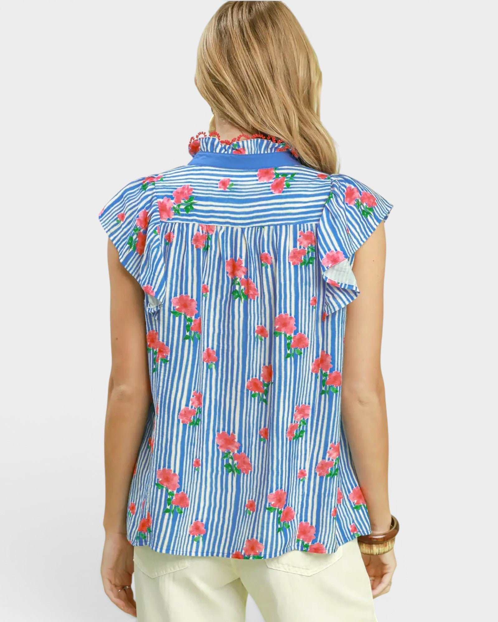 Woman wearing a sleeveless floral and striped shirt on a white background