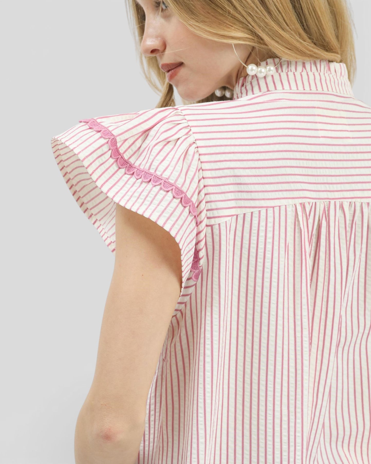 Woman wearing a red and white striped dress with lace details on a plain background