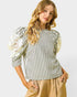 Woman wearing a black and white striped blouse with puff sleeves on a light gray background