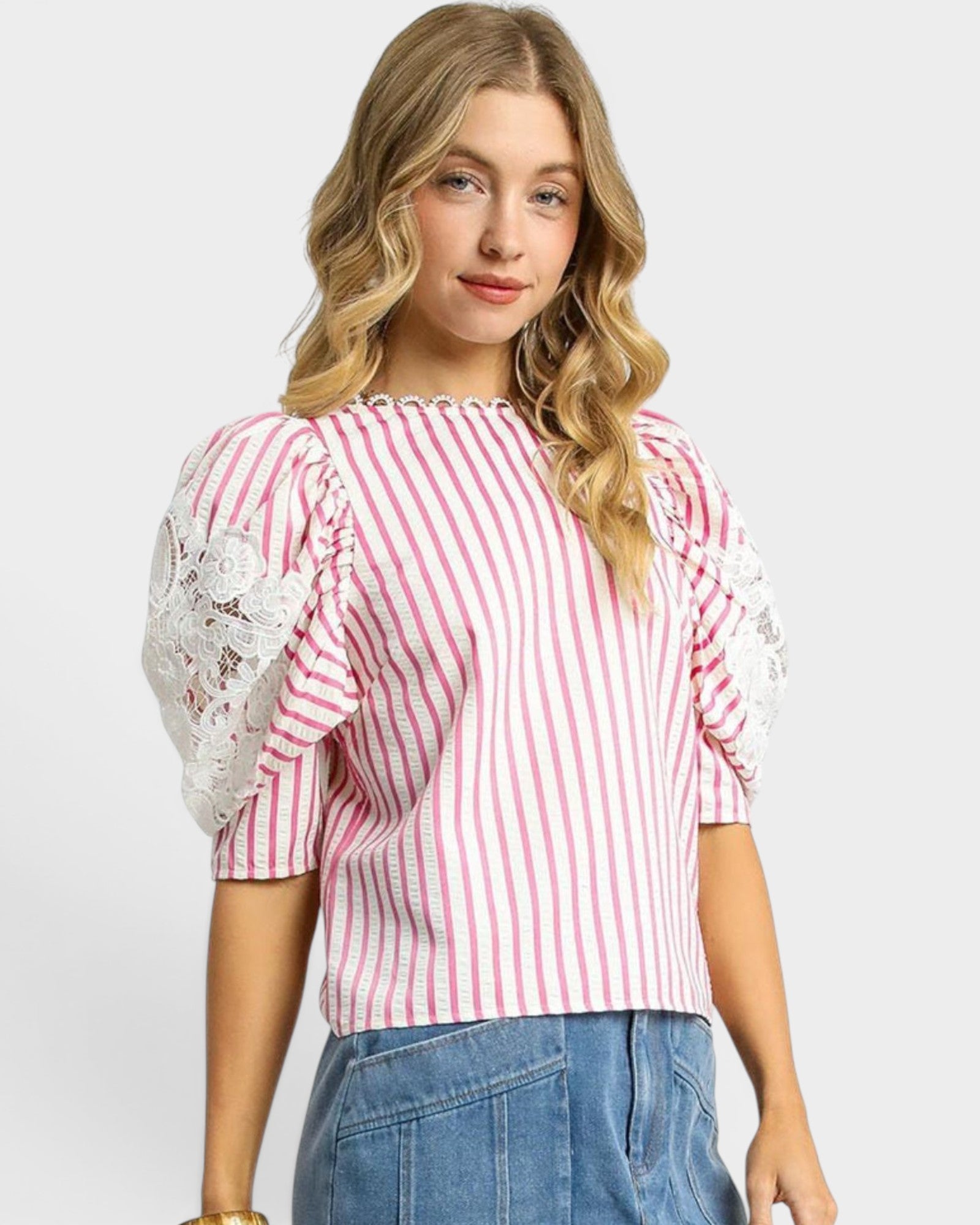 Woman wearing a red and white striped top with lace sleeves on a plain background